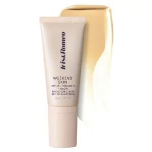 Na zdjęciu widzimy opakowanie produktu kosmetycznego "Weekend Skin" marki Iris & Romeo. Jest to krem z ochroną przeciwsłoneczną SPF 50, wzbogacony o witaminę C, mający na celu zapewnienie skórze ochrony przed promieniowaniem UV oraz dodatkowego rozświetlenia. Opakowanie ma prosty, minimalistyczny design w jasnym odcieniu z wyraźnie widocznymi na froncie czarnymi literami informującymi o nazwie produktu i jego głównych cechach. Produkt prezentowany jest w sposób, który podkreśla jego funkcję ochronną i pielęgnacyjną, co jest istotne dla konsumentów szukających skutecznych rozwiązań w zakresie ochrony skóry. Delikatny, kremowy odcień opakowania kojarzy się z łagodnością i bezpieczeństwem, co może przyciągać uwagę osób dbających o zdrowy wygląd skóry na co dzień.