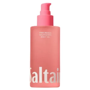 Na obrazku znajduje się różowa butelka olejku do ciała Saltair "PINK BEACH NOURISHING BODY OIL". Butelka ma matowe wykończenie i wyposażona jest w różową pompkę do wygodnego dozowania produktu. Na froncie butelki widnieje napis "PINK BEACH NOURISHING BODY OIL", podkreślający nazwę i właściwości olejku. U dołu butelki znajduje się duże logo marki „Saltair” w białym kolorze, które jest dobrze widoczne na różowym tle. Całość prezentuje się elegancko i nowocześnie, sugerując, że produkt jest przeznaczony do intensywnej pielęgnacji i nawilżania skóry.