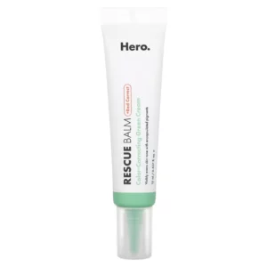 Na zdjęciu widoczny jest produkt Hero Cosmetics Rescue Balm +Red Correct, korekcyjny zielony krem do skóry o działaniu łagodzącym. Biało-zielona tubka o minimalistycznym designie zawiera informację o właściwościach produktu, takich jak neutralizowanie zaczerwienień oraz regeneracja skóry. Produkt ma pojemność 15 ml i został stworzony do wyrównywania kolorytu skóry, szczególnie dla osób z problemem zaczerwienień.