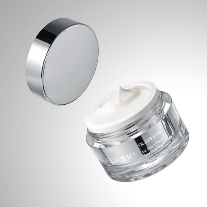 Lepique Glass Skin Retinol Night Cream Na zdjęciu znajduje się luksusowy słoiczek kremu Lepique Glass Skin 14 Days Miracle Retinol Night Cream o eleganckim, przezroczystym opakowaniu i srebrnym wieczku unoszącym się nad słoiczkiem. Wewnątrz widoczny jest biały krem o gładkiej, kremowej konsystencji, gotowy do aplikacji. Minimalistyczny design opakowania w srebrnych i białych tonacjach podkreśla ekskluzywność produktu, który obiecuje widoczne efekty w postaci "szklanej skóry" już po 14 dniach stosowania. Produkt dedykowany do nocnej pielęgnacji skóry, idealny dla osób poszukujących intensywnego nawilżenia i regeneracji.