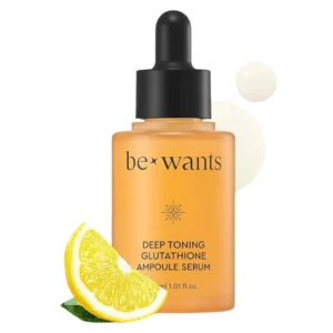 Butelka serum Bewants Deep Toning Glutathione Ampoule Serum o eleganckim, bursztynowym kolorze z czarną pipetą. Na pierwszym planie soczysta połówka cytryny symbolizuje obecność witaminy C w formule. W tle delikatne, mleczne krople sugerują lekką i nawilżającą konsystencję produktu.