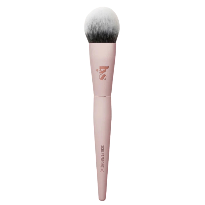 Lys Beauty Sculpting Brush (3) Zbliżenie na pędzel do konturowania marki LYS Beauty. Pędzel ma ergonomiczny, różowy trzonek i zaokrągloną główkę z białym włosiem przechodzącym w czarny kolor na końcach. Na trzonku znajduje się napis „SCULPT | BRONZING”.