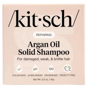 Opakowanie szamponu w kostce marki Kitsch. Na beżowym tle widnieje nazwa produktu: "Argan Oil Solid Shampoo". Opakowanie informuje, że produkt jest bezpieczny dla koloru włosów, zrównoważony pod względem pH i wystarcza na 100 myć. Jest także cruelty-free.