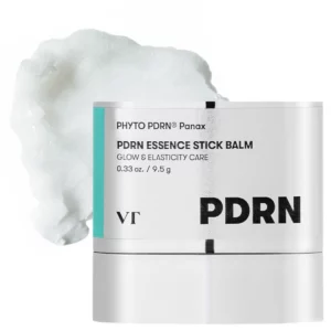 Balsam VT PDRN Essence Stick Balm na tle rozprowadzonej białej esencji, podkreślający kremową konsystencję produktu.