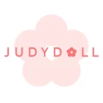 Logo marki Judydoll w odcieniach różu – stylizowany napis „JUDYDOLL” z małym kwiatkiem zastępującym literę „O”, umieszczony na tle dużego, jasnoróżowego kwiatu o pięciu płatkach.