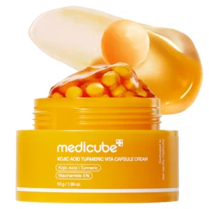 Otwarty słoiczek kremu Medicube Kojic Acid Turmeric Vita Capsule Cream z widocznymi żółtymi kapsułkami i żelową konsystencją na wieczku.