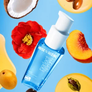 Niebieska butelka serum Mise en Scène Perfect Hydrating Serum otoczona naturalnymi składnikami, takimi jak kokos, kwiat kamelii, brzoskwinia i krople oleju. Kompozycja podkreśla odżywczy charakter produktu.