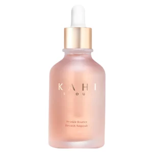Packshot ampułki KAHI Wrinkle Bounce Blemish Ampoule na jasnym tle. Matowa szklana butelka w odcieniu różowo-brzoskwiniowym wyposażona jest w pipetę z jasną gumową końcówką i złotą nakrętkę. Na froncie widoczne jest logo KAHI Seoul.