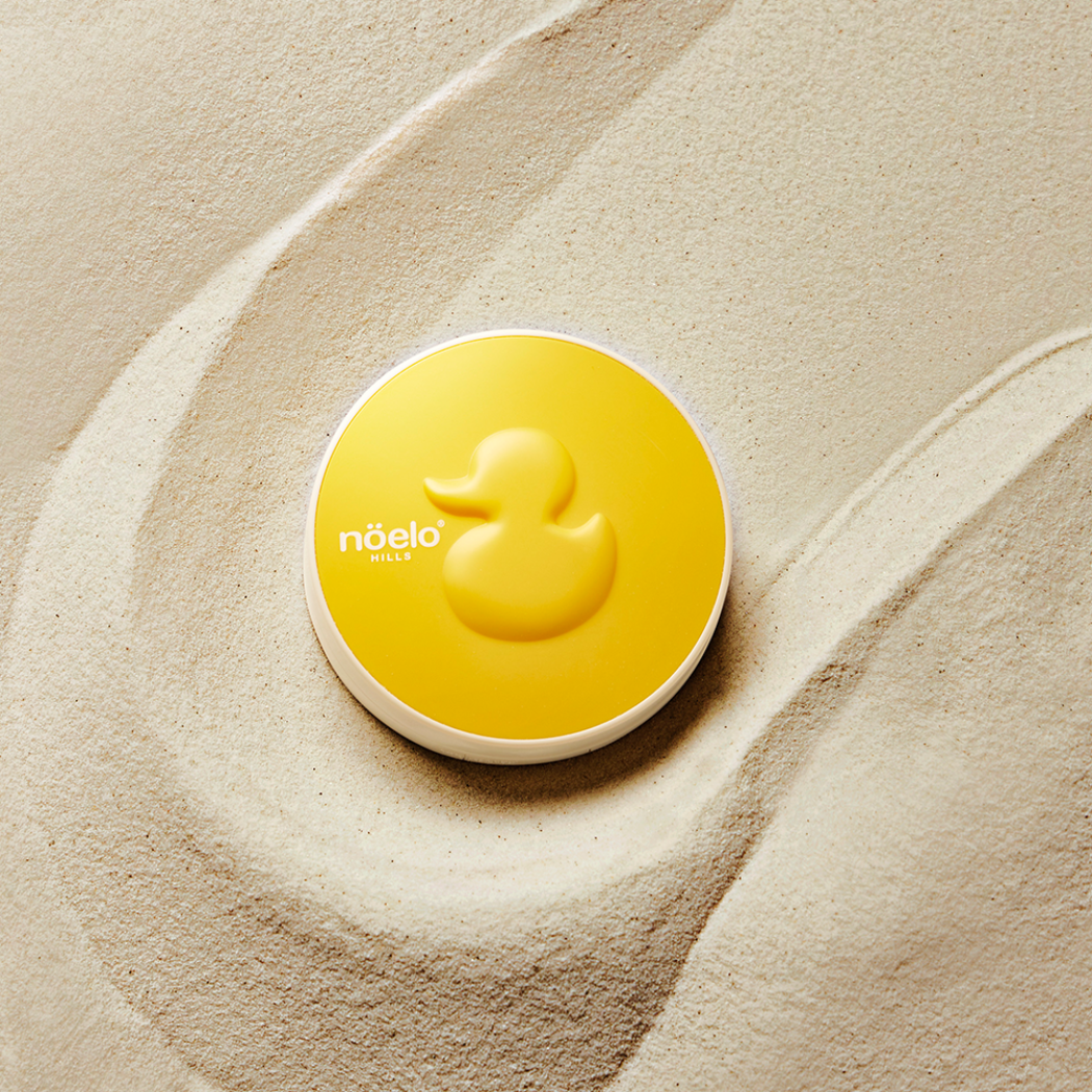 Noelo Hills Skin Barrier Sun Cushion SPF 50 Noelo Hills Skin Barrier Sun Cushion SPF50+ PA++++ prezentowany na jasnym piasku. Delikatna ochrona przeciwsłoneczna dla dzieci, niemowląt i skóry wrażliwej.