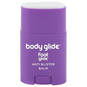 Fioletowy sztyft Body Glide Foot Glide Anti Blister Balm pokazany frontem na białym tle, z widocznym białym balsamem i pokrętłem u podstawy.