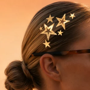 Zbliżenie na gładko zaczesane włosy ozdobione błyszczącymi złotymi gwiazdkami Fazit Golden Starlet Strands.