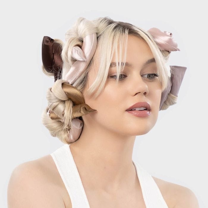 Kitsch Satin Flexi Rods Blondynka z włosami owiniętymi wokół satynowych wałków Kitsch Flexi Rods, przygotowująca loki bez użycia ciepła.