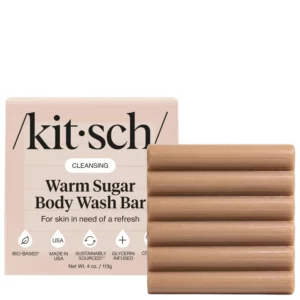 Kitsch Warm Sugar Body Wash Bar – produkt i opakowanie – beżowa żłobiona kostka myjąca ustawiona obok różowego opakowania Kitsch Warm Sugar Body Wash Bar na białym tle.