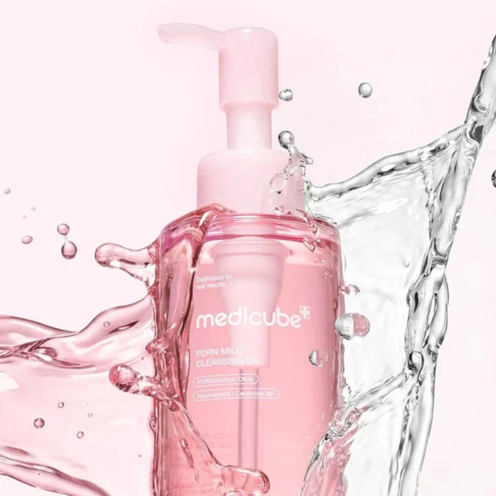 Medicube PDRN Mild Cleansing Oil Medicube PDRN Mild Cleansing Oil – różowa butelka olejku do demakijażu otoczona efektownym rozpryskiem wody.