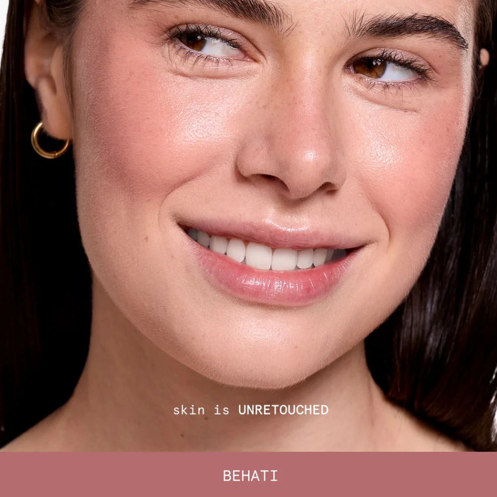 behati ciele blush Na zdjęciu znajduje się uśmiechnięta modelka z naturalnie widoczną teksturą skóry i subtelnym, przygaszonym różem do policzków w odcieniu Behati.
