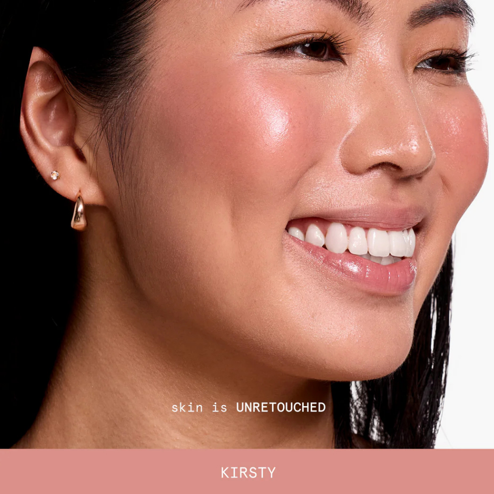 kirsty ciele blush Na zdjęciu znajduje się uśmiechnięta modelka z miękkim, stonowanym różowo-brzoskwiniowym odcieniem Kirsty na policzkach.