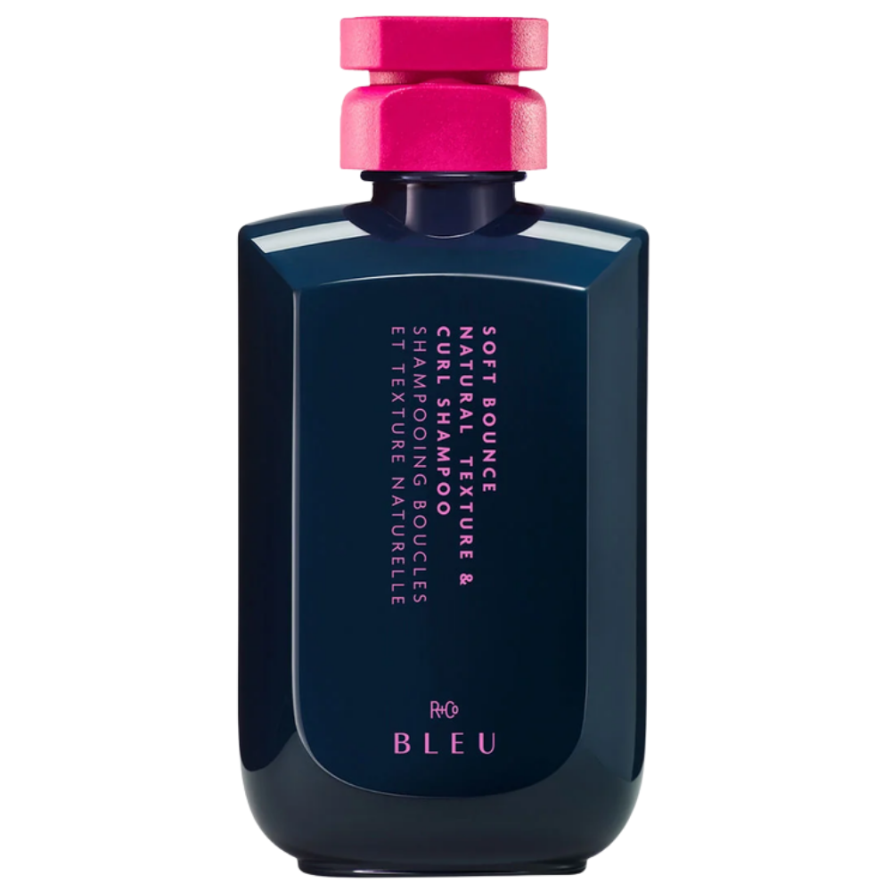 R+Co BLEU Soft Bounce Natural Texture & Curl R+Co BLEU Soft Bounce Natural Texture & Curl Shampoo w granatowej butelce z intensywnie różową nakrętką na białym tle.