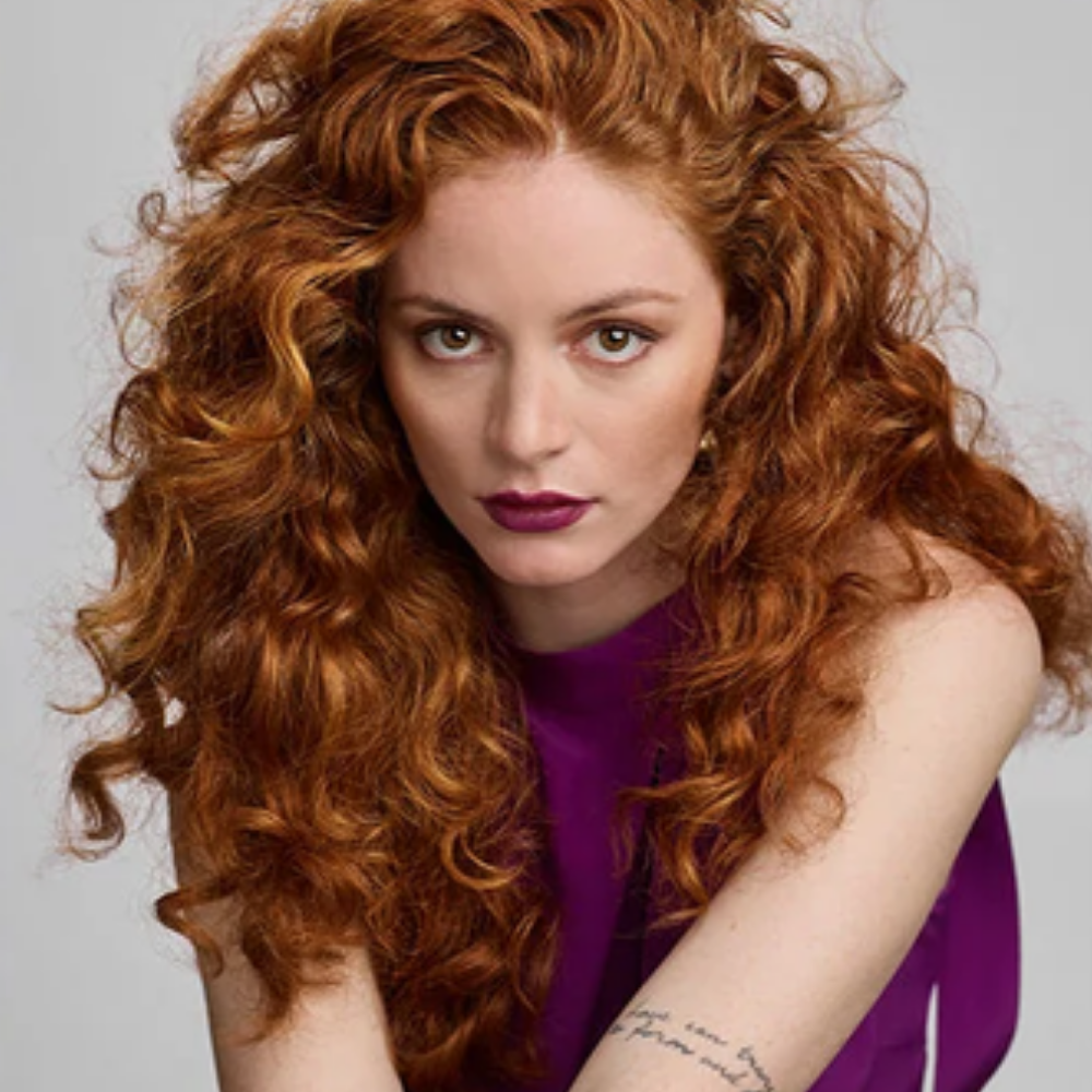 R+Co BLEU Soft Bounce Natural Texture & Curl Conditioner Odżywka R+Co BLEU Soft Bounce Natural Texture & Curl Conditioner ułożona na betonowej powierzchni w słońcu, obok pozostałych kosmetyków z kolekcji.
