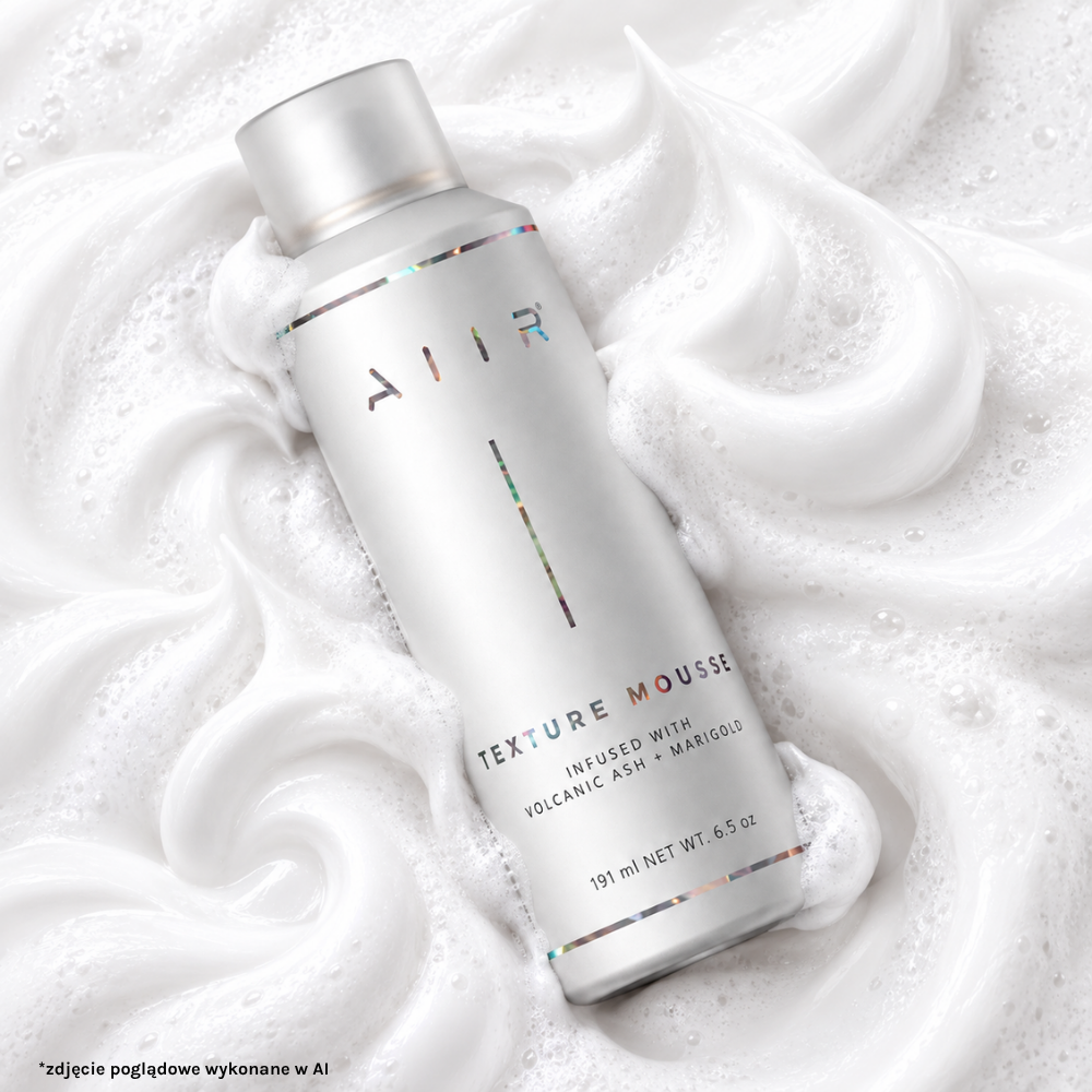 Aiir Dry Texture Mousse AIIR Dry Texture Mousse - srebrne opakowanie musu do stylizacji włosów pokazane na tle puszystej, białej pianki. Minimalistyczna aranżacja podkreśla lekką konsystencję produktu przeznaczonego do nadawania włosom objętości i tekstury.