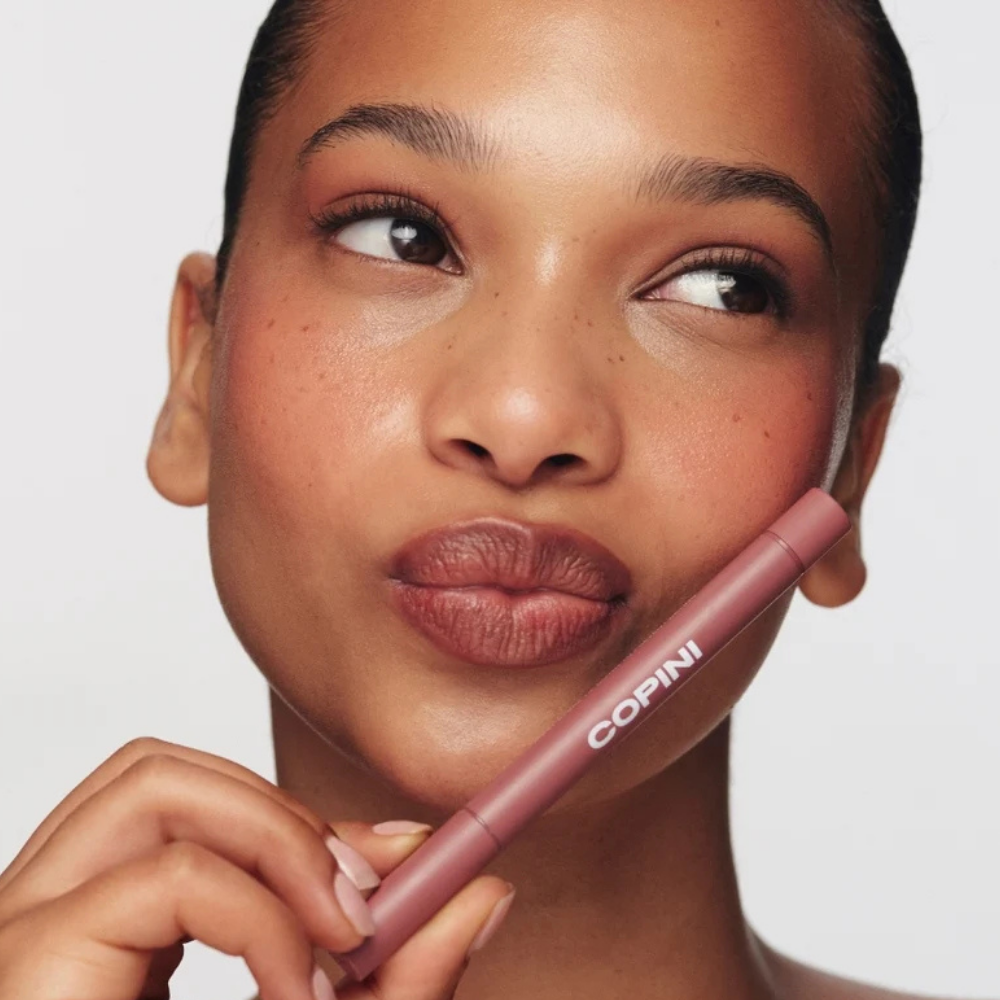 Copini Love Bite Soft Focus Lip Stain (9) Copini Love Bite Soft Focus Lip Stain - efekt Toasted - modelka prezentująca ciepły brązowy odcień Toasted na ustach oraz produkt Copini.