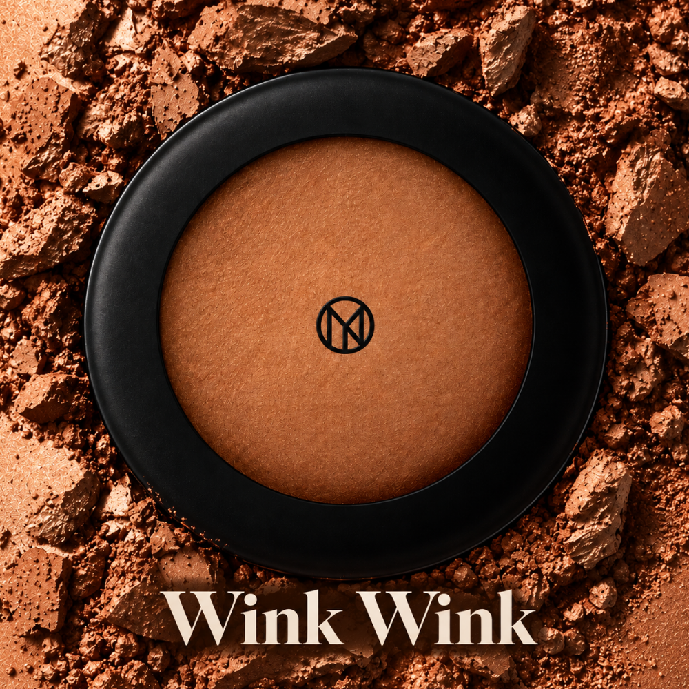 IL MAKIAGE Mineral Baked Bronzer - mineralny wypiek słońca IL MAKIAGE Mineral Baked Bronzer w odcieniu Wink Wink - wypiekany bronzer w ciepłym, głębokim brązowym odcieniu, w czarnym okrągłym opakowaniu, na tle rozkruszonego pigmentu w dopasowanej tonacji.