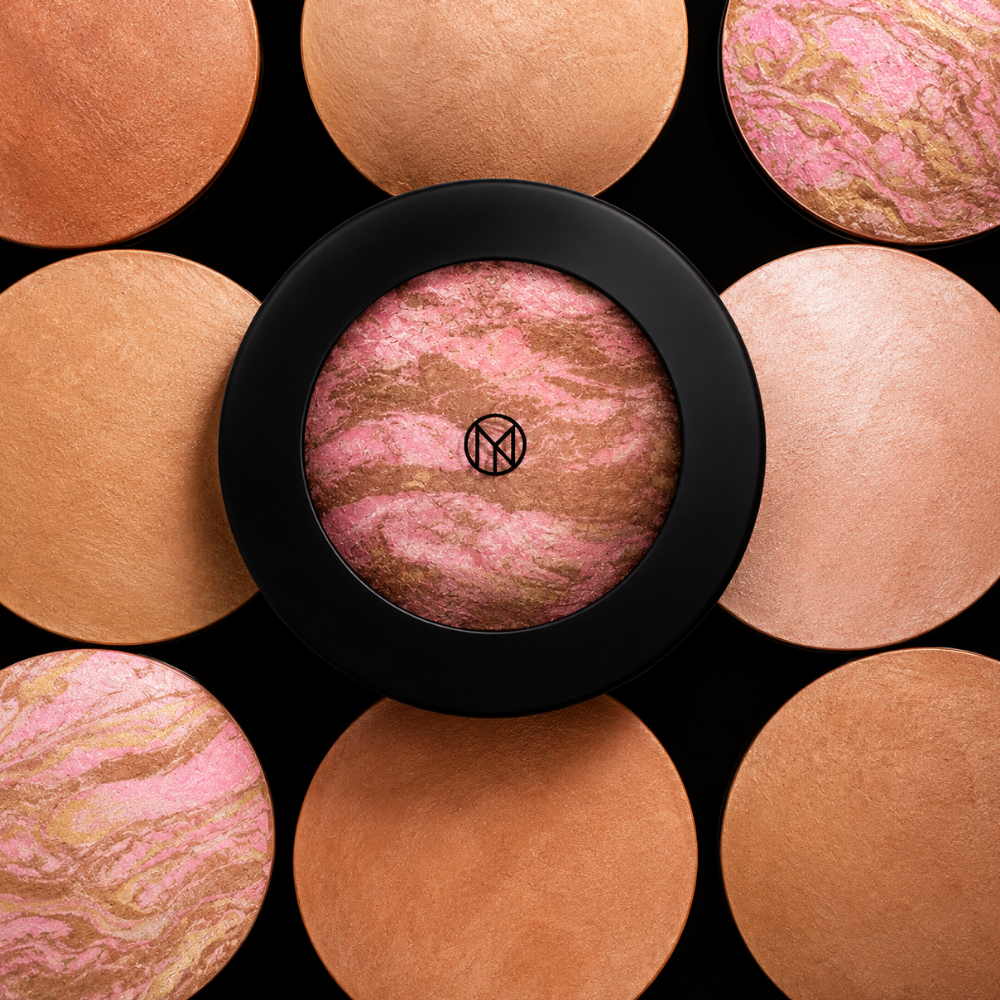 IL MAKIAGE Mineral Baked Bronzer - mineralny wypiek słońca (2) IL MAKIAGE Mineral Baked Bronzer - kompozycja wypiekanych bronzerów w ciepłych beżowych, brązowych, brzoskwiniowych i różowo-złotych odcieniach, z centralnym marmurkowym bronzerem w czarnym opakowaniu, na eleganckim czarnym tle.