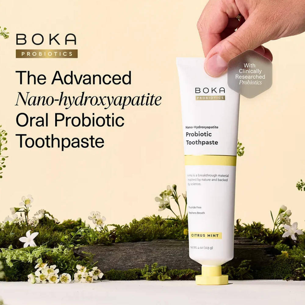 Citrus Mint Probiotic Nano-hydroxyapatite Toothpaste (3) Boka Citrus Mint Probiotic Toothpaste - nowoczesna pasta do zębów z nanohydroksyapatytem i probiotykami, opracowana z myślą o pielęgnacji szkliwa i mikrobiomu jamy ustnej. Biała tubka z żółtymi akcentami prezentowana na naturalnym tle z mchem i kwiatami.