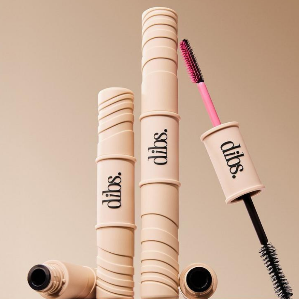 Dibs Double Standard Burgundy Primer & Mascara Duo (4) DIBS Double Standard Burgundy Primer & Mascara Duo - dwustronna maskara i burgundowa baza wydłużająca rzęsy w eleganckim, beżowym opakowaniu z logo DIBS. Na beżowym tle widoczne opakowania kosmetyku oraz dwie szczoteczki: różowa do burgundowej bazy tubingowej i czarna do maskary zwiększającej objętość rzęs.