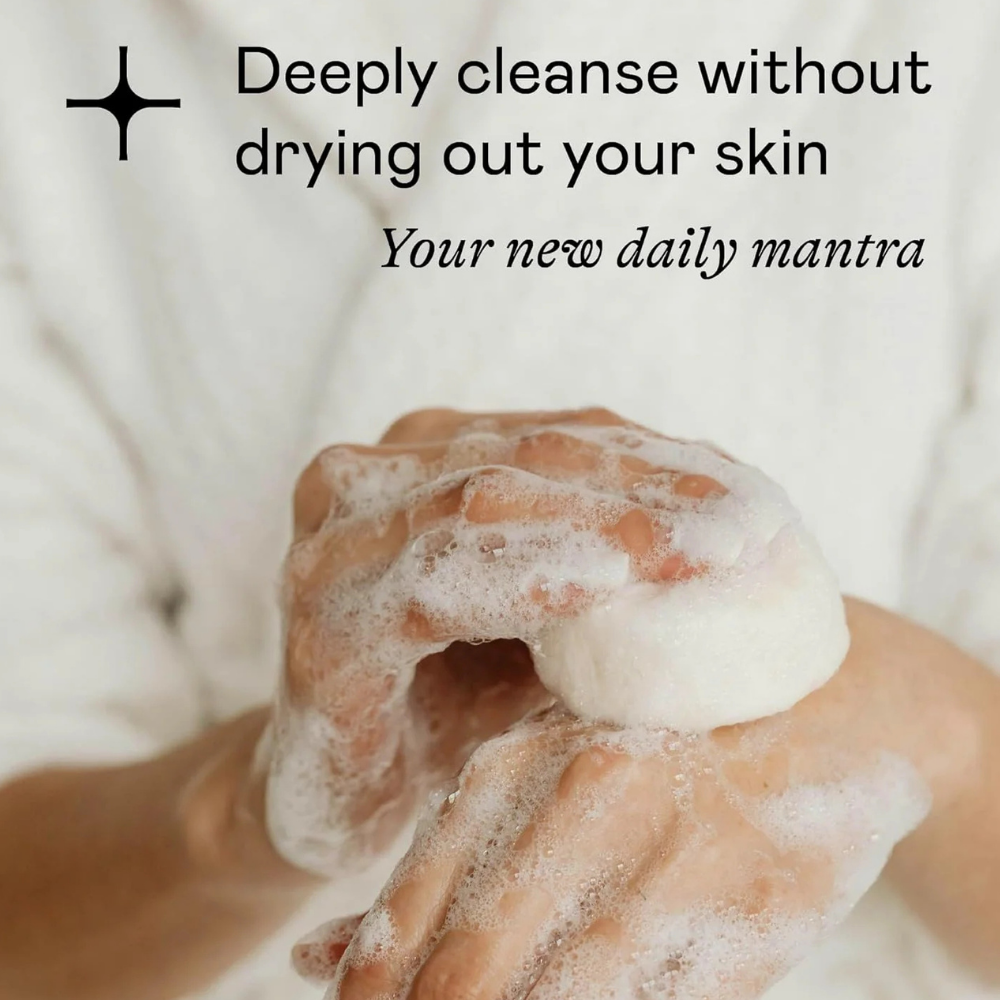 Doc & Glo Daily Mantra Boosting Body Wash (3) Dłonie pokryte obfitą, delikatną pianą podczas mycia skóry żelem Doc & Glo Daily Mantra Boosting Body Wash. Grafika na jasnym, kremowym tle podkreśla głębokie oczyszczanie bez przesuszania skóry oraz codzienny rytuał pielęgnacyjny zapewniający uczucie świeżości i komfortu.