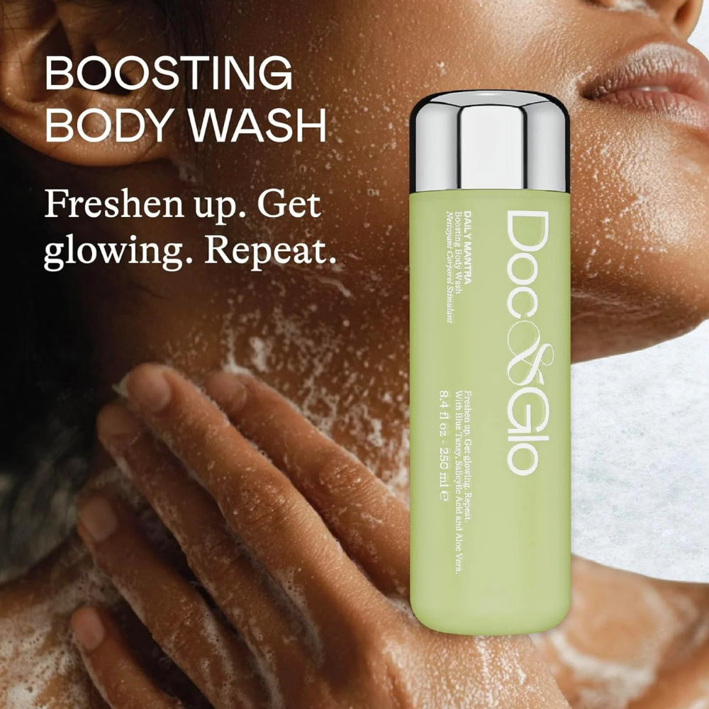 Doc & Glo Daily Mantra Boosting Body Wash (6) Doc & Glo Daily Mantra Boosting Body Wash - odświeżający żel do mycia ciała w jasnozielonej butelce ze srebrną nakrętką, na tle kobiety masującej szyję i dekolt pokryte delikatną pianą. Grafika podkreśla oczyszczające, odświeżające i wygładzające właściwości kosmetyku oraz codzienny rytuał pielęgnacji skóry.