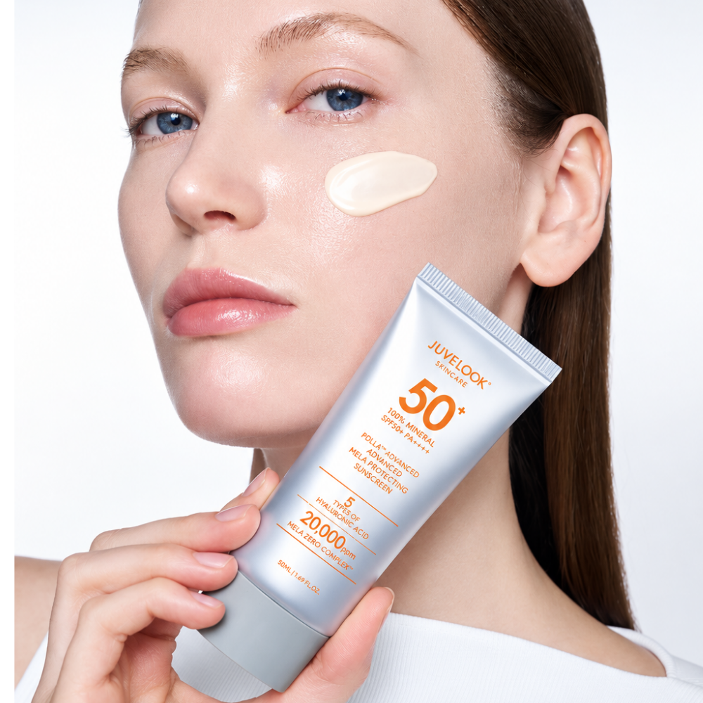 Juvelook PDLLA Advanced Mela Protecting Sunscreen SPF50 - spf do skóry po zabiegach i z przebarwieniami (3) JUVELOOK PDLLA Advanced Mela Protecting Sunscreen SPF50+ - aplikacja na skórę - modelka trzymająca mineralny krem przeciwsłoneczny JUVELOOK przy twarzy, z widoczną kremową konsystencją produktu na policzku.