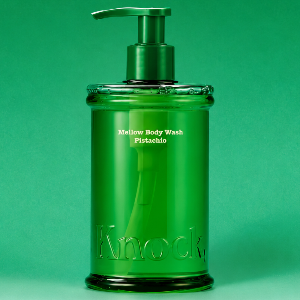 Knock Pistachio Mellow Body Wash - kremowy żel pod prysznic z efektem jedwabistej skóry Knock Mellow Body Wash Pistachio 300 ml - pistacjowy żel pod prysznic w eleganckiej, transparentnej zielonej butelce z pompką i wytłoczonym logo Knock, przedstawiony na zielonym tle.