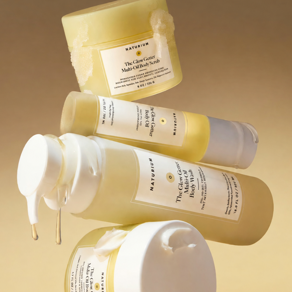 Naturium The Glow Getter (2) Zestaw czterech kosmetyków do pielęgnacji ciała Naturium The Glow Getter na ciepłym, beżowo-złotym tle. Na zdjęciu peeling Multi-Oil Body Scrub, olejek Body Oil, żel pod prysznic Multi-Oil Body Wash oraz masło do ciała Multi-Oil Body Butter. Żółte opakowania otoczone kremowymi konsystencjami podkreślają odżywczy charakter pielęgnacji.