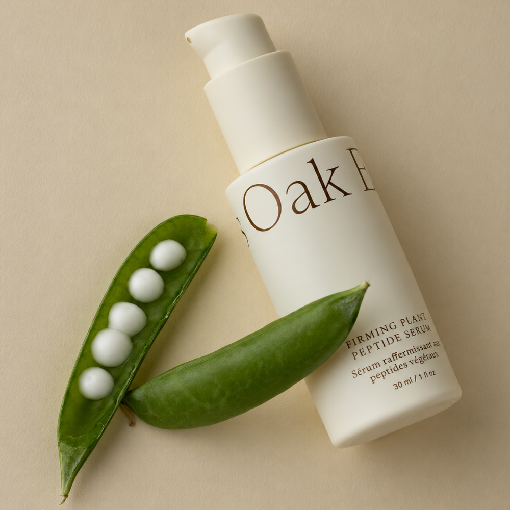 Oak Essentials Firming Plant Peptide Serum Oak Essentials Firming Plant Peptide Serum 30 ml - peptydowe serum do twarzy w kremowej butelce z pompką, przedstawione z zielonymi strąkami grochu na beżowym tle.