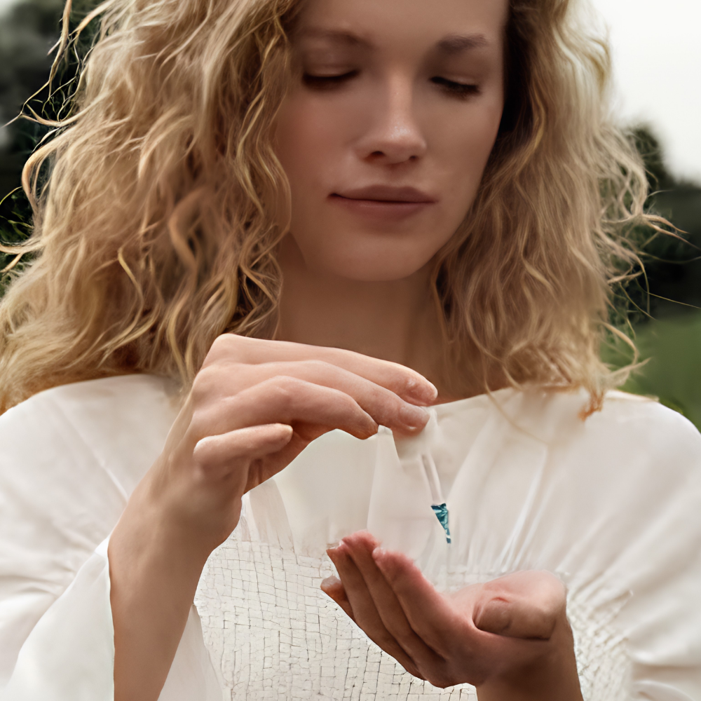 Oak Essentials Ritual Oil (3) Kobieta aplikująca Oak Essentials Ritual Oil na dłoń - lekki olejek do twarzy z Blue Tansy wspierający nawilżenie, ukojenie i komfort skóry.