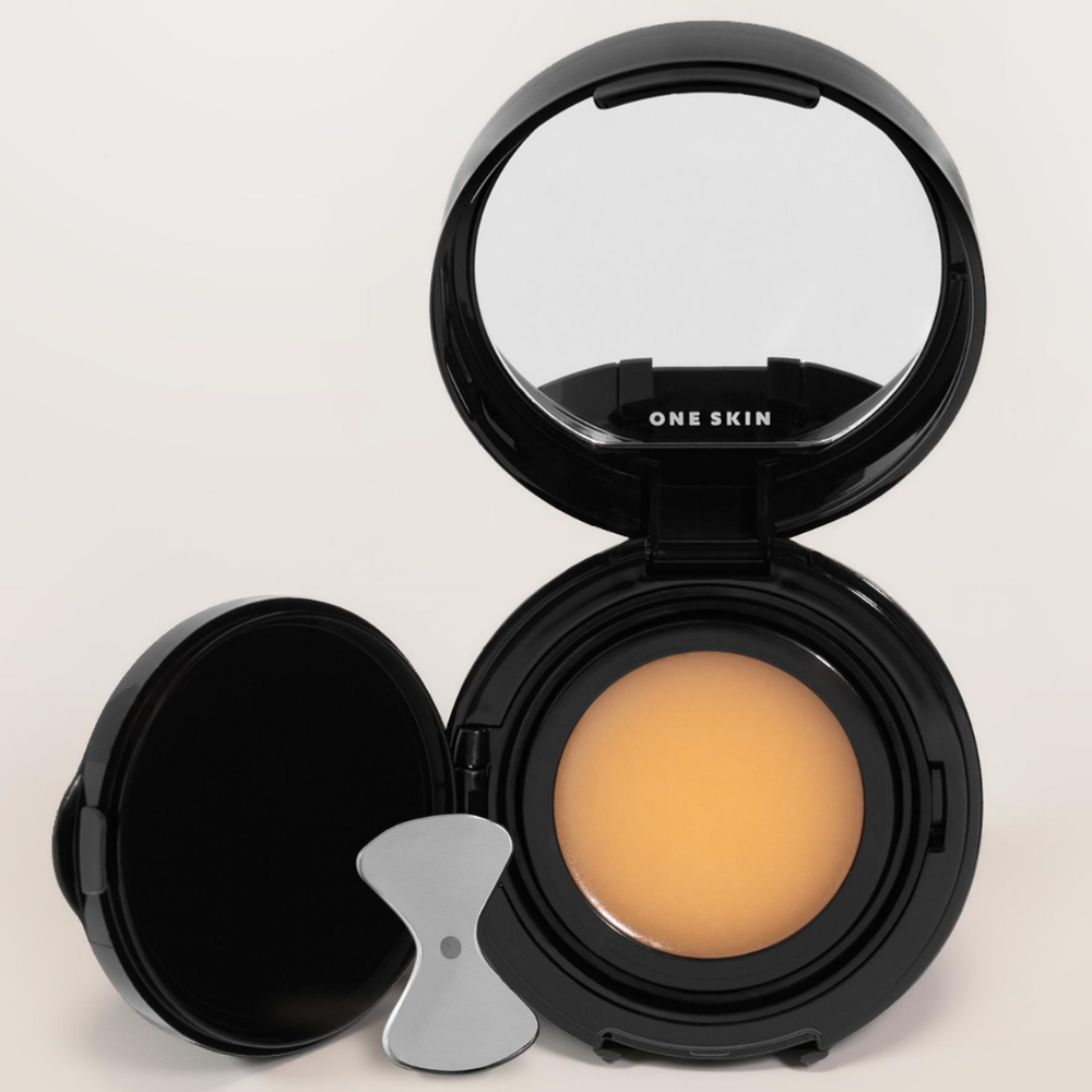 One Skin Os 01 Lip Peptide Lip Mask ONE SKIN - kosmetyk do makijażu twarzy w ciepłym beżowym odcieniu, przedstawiony w otwartym, eleganckim czarnym kompakcie z lusterkiem, wewnętrzną pokrywką ochronną i aplikatorem. Minimalistyczne opakowanie na jasnym, neutralnym tle.