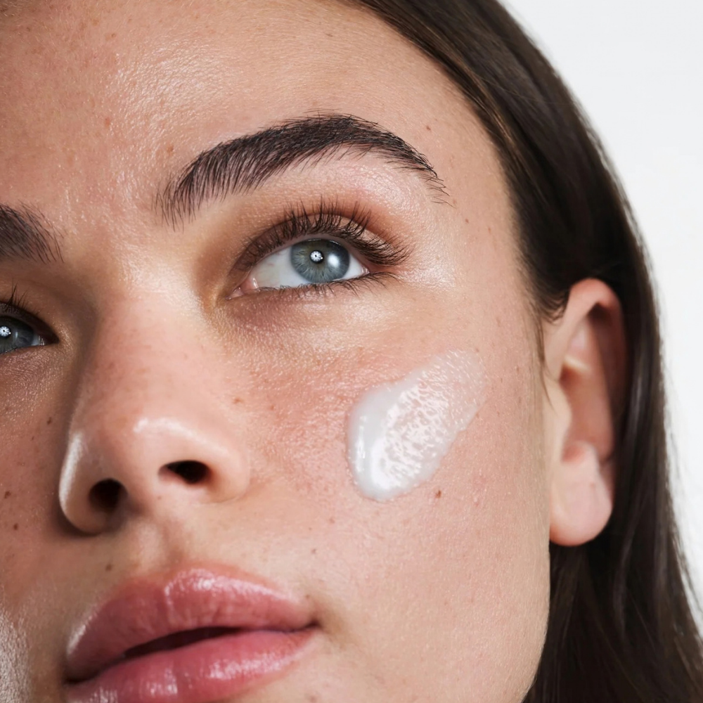 Reale Actives Go Calm Serum (3) Reale Actives Go Calm - zbliżenie twarzy modelki z nałożoną na policzek kremową formułą serum do skóry skłonnej do zaczerwienień i niedoskonałości.
