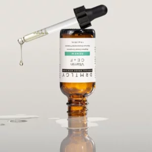 zdjęcie przedstawia serum z witaminą C, E i F które jest odwrócone do góry nogami, na szarym tle