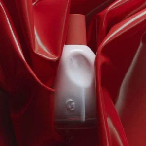 Lifestyle 13 Świąteczny zestaw balsamów Glossier Balm Dotcom Duo, zawierający dwie tubki balsamów w smakach „Biscotti” i „Espresso”, umieszczony w głębokim bordowym pudełku w kształcie ciastka z dopasowaną wstążką. Obok znajduje się ciastko biscotti oraz filiżanka espresso, które wzmacniają przytulny, świąteczny klimat.