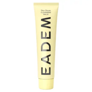 Żółta tuba produktu Eadem Dew Dream Cleansing Balm ustawiona pionowo na białym tle. Na opakowaniu dużymi, czarnymi literami widnieje logo EADEM, a powyżej znajduje się nazwa produktu: Dew Dream Cleansing Balm. Minimalistyczny i nowoczesny design.
