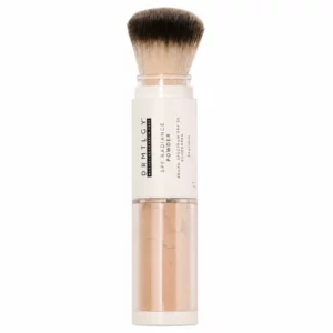 Puder mineralny DRMTLGY SPF Radiance Powder SPF 30 w odcieniu Medium Tan z aplikatorem w formie miękkiego pędzla, pokazany na białym tle.