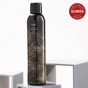 Oribe Dry Texturizing Spray – luksusowy spray teksturyzujący do włosów w czarnej butelce ze złotym wzorem, produkt do objętości i stylizacji na jasnym tle
