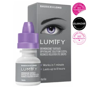 Opakowanie i buteleczka kropli do oczu Lumify marki Bausch + Lomb. Szare pudełko z fioletowym okiem i białymi napisami informuje, że produkt redukuje zaczerwienienie oczu w 1 minutę i działa do 8 godzin. Obok opakowania znajduje się buteleczka z fioletową zakrętką. Po prawej stronie widoczne są trzy odznaczenia nagród kosmetycznych: NewBeauty 2022 i 2023 oraz Glamour 2022.