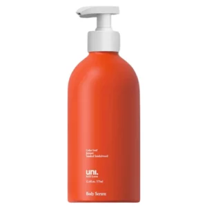 Czerwona butelka z białą pompką, zawierająca serum do ciała. Na butelce znajduje się tekst: "Cedar Leaf Juniper Smoked Sandalwood, uni. Refill System, 12.6 fl. oz / 375 ml, Body Serum
