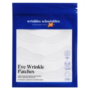 "Niebieska saszetka Wrinkles Schminkles Eye Wrinkle Patches z sześcioma przezroczystymi silikonowymi płatkami pod oczy widocznymi pod białym okienkiem. Na dole umieszczony jest napis Eye Wrinkle Patches oraz ikony informujące o produkcji w USA, liczbie płatków i liczbie użyć."