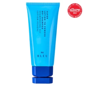Na zdjęciu znajduje się niebieska tubka suchego szamponu „Vapor Lotion to Powder Dry Shampoo” marki R+Co BLEU z ciemnoniebieską zakrętką i napisem.