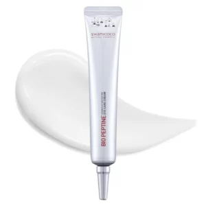 Zdjęcie przedstawia srebrną tubkę kremu pod oczy marki Swanicoco o nazwie "Bio Peptine Eye Care Cream". Na tubce widnieje logo marki oraz czerwony napis podkreślający nazwę produktu. Tło zdobi subtelne tło w odcieniach bieli, na którym widoczna jest rozsmarowana próbka kremu, wskazująca na jego lekką i kremową konsystencję. Produkt przeznaczony jest do pielęgnacji skóry wokół oczu.