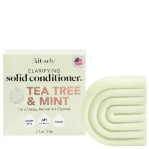 Zdjęcie przedstawia Kitsch Clarifying Solid Conditioner Tea Tree & Mint – odżywkę w kostce o jasnozielonym kolorze i geometrycznym kształcie. Opakowanie informuje o jej oczyszczających właściwościach, wegańskiej formule oraz bezpieczeństwie dla koloru.