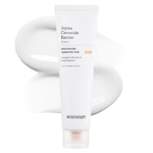 Biała tubka kremu Jojoba Ceramide Barrier Cream od Meditherapy na tle rozsmarowanego produktu. Na opakowaniu widnieją kluczowe składniki: niacynamid i kwas hialuronowy, które wzmacniają barierę skórną i zapewniają głębokie nawilżenie. Minimalistyczny design podkreśla dermatologiczny charakter kosmetyku. Pojemność: 100 ml.