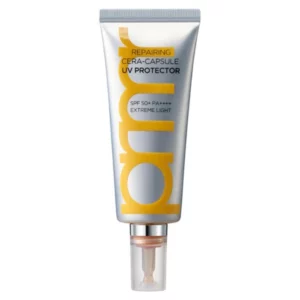 Srebrna tubka kremu przeciwsłonecznego Primera Repairing Cera-Capsule UV Protector z żółtymi i czarnymi napisami. Produkt oferuje ochronę SPF 50+ PA++++ i ma lekką, regenerującą formułę. Na opakowaniu widnieje napis „Extreme Light”, co sugeruje, że krem ma ultralekką konsystencję. Tubka posiada precyzyjny aplikator, który ułatwia dozowanie produktu.